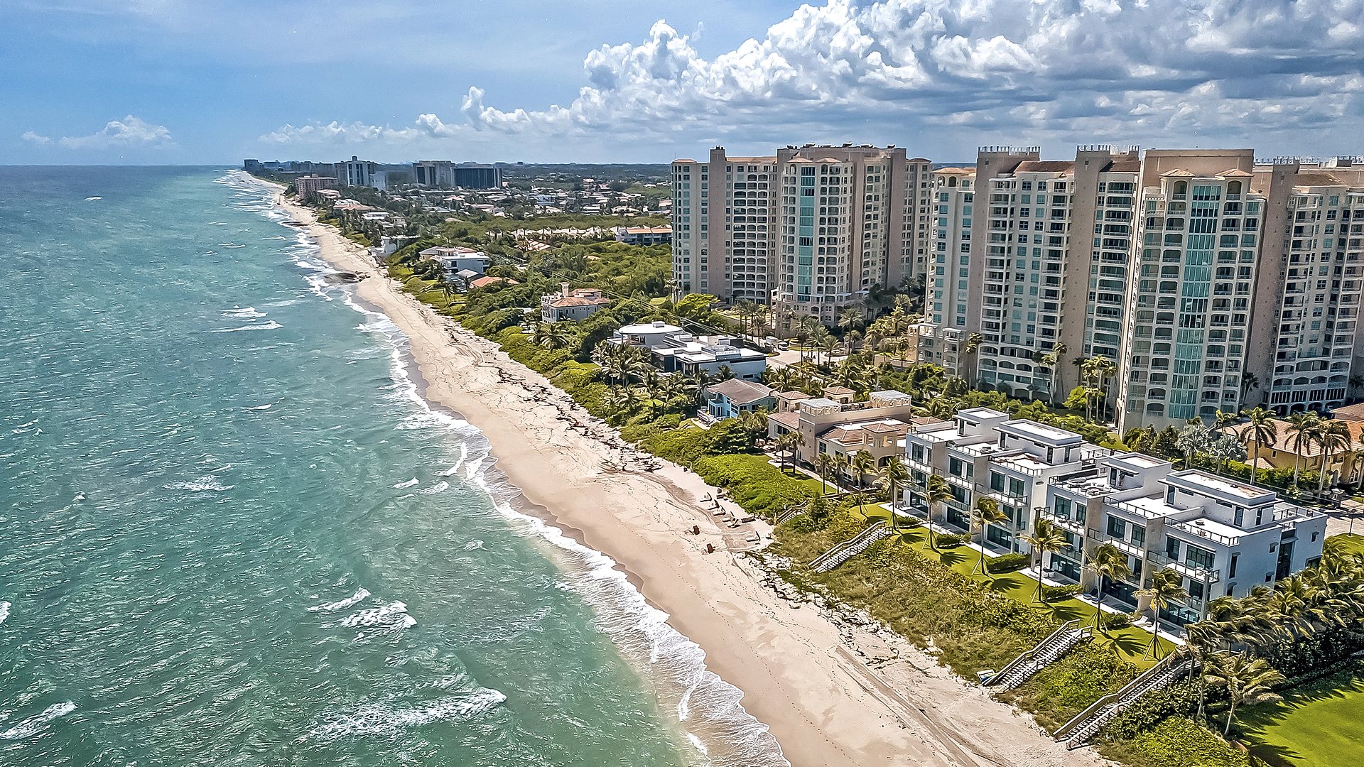 The Highland Beach shoreline looking north along A1A, with oceanfront condominium towers and townhomes between the Atlantic and the Intracoastal Waterway